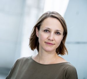 Eine Frau mit halblangen braunen Haaren. Sie schaut freundlich in die Kamera.
